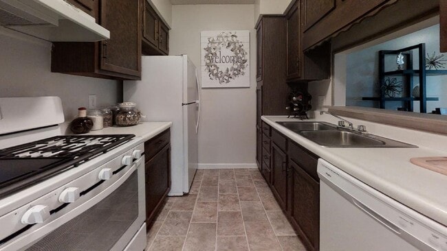 Spacious kitchen with natural wood cabinets, a stove, and open counter space, creating a homely cooking environment. - Wilshire Apartments