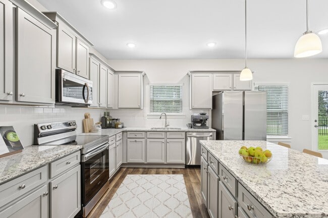 Spacious kitchen with an island, ample storage, stainless steel appliances and view into the living room.