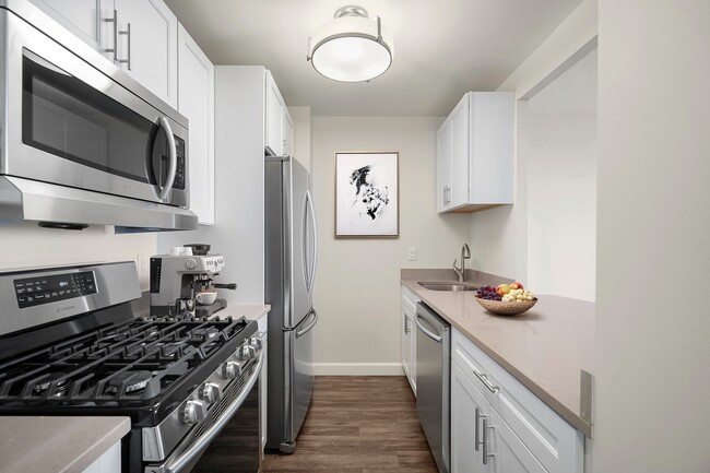 Modern kitchen with six-burner gas stove, sleek stainless steel appliances, elegant cabinetry, stone countertops and large refrigerator at Parkside Place, apartments in Cambridge, MA