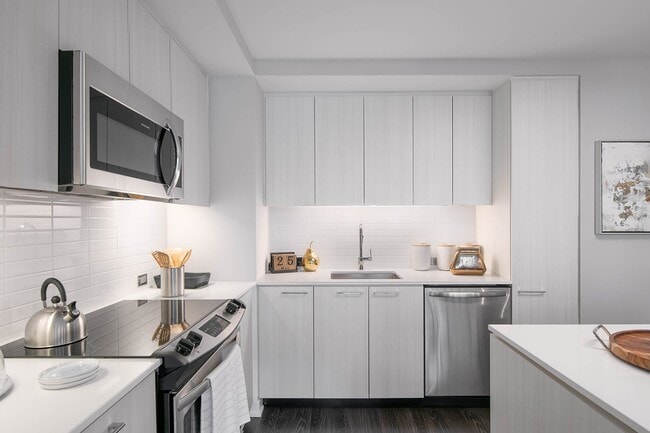 Contemporary kitchens include glass tile backsplash, premium quartz countertops, and designer lighting - Signature Reston Town Center Apartments