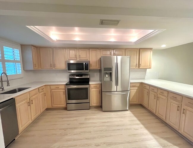 open plan kitchen with quartz countertops and stainless steel appliances - 6660 Ilex Cir Condo Unit F