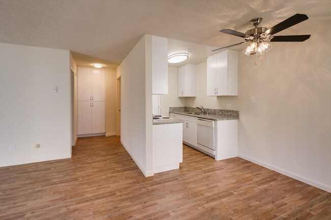 Cocina con gabinetes blancos, encimeras de formica, pisos de tablones estilo madera, y la vista del área del comedor. - Casa De La Mesa Apartamentos