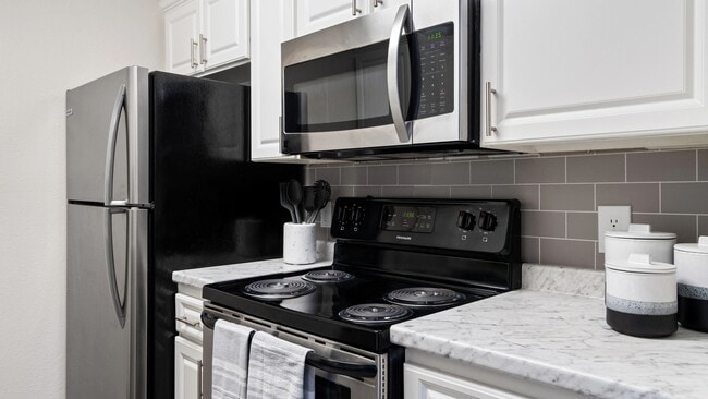 This modern kitchen featuring stainless steel appliances, elegant white cabinetry, and a sleek subway tile backsplash is perfect for home cooking and entertaining.