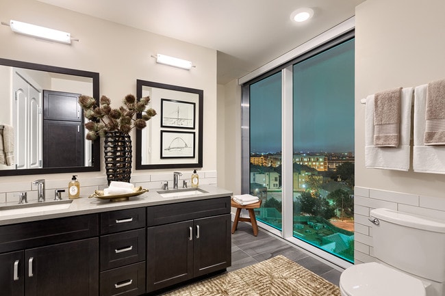 Baños de lujo con ventanas grandes, gabinetes de color oscuro y espejos enmarcados