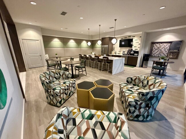 Integra Palms offers a stylish communal lounge featuring modern geometric chairs, cozy lighting, and a sleek kitchen area. - Integra Palms Apartments