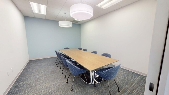 Modern conference room with a sleek wooden table, stylish chairs, and elegant lighting, ideal for productive meetings.