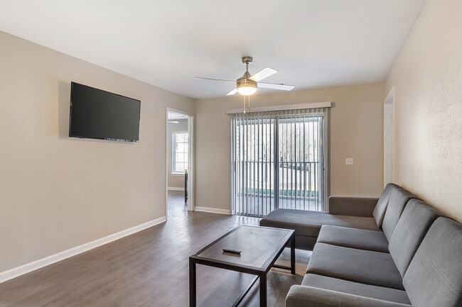 Experience comfort and style in this spacious living room, complete with modern amenities and natural light. - Village Green Student Housing