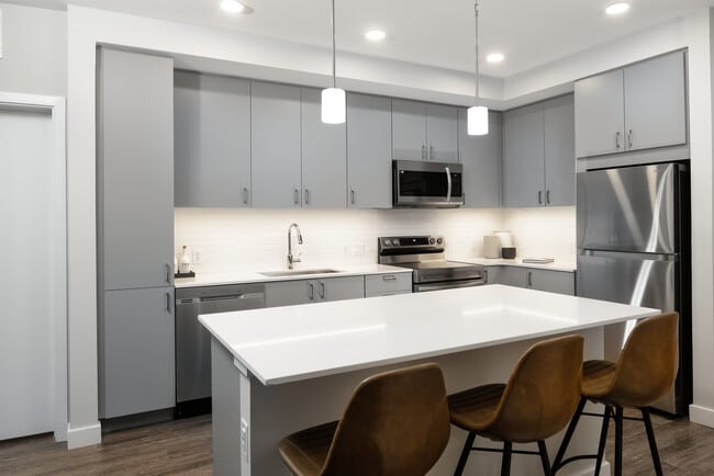 Modern kitchens with light grey cabinetry, white quartz countertops, stainless steel appliances, and hard surface flooring - Avalon Brighton Apartments