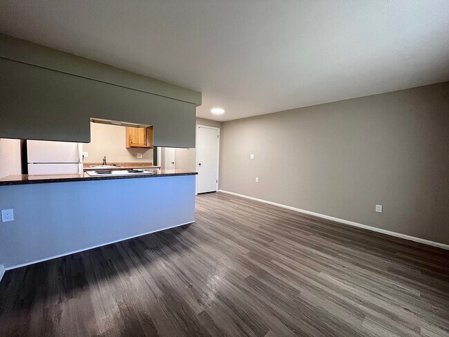 Bright and spacious apartment interior with modern hardwood floors, open kitchen area, and minimalist design.