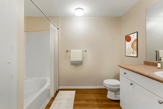 Renovated Package I bath with neutral laminate countertop, white cabinetry, and upgraded hard surface flooring
