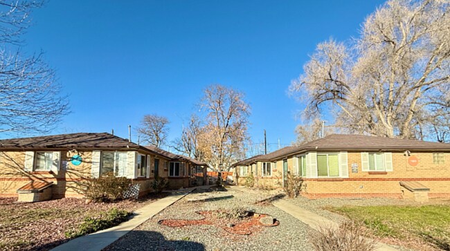 Encantadores dúplex de ladrillo con amplios patios delanteros y un cielo azul claro en un entorno de vecindario tranquilo. - Flats at 16th
