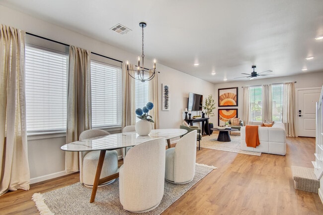 Dining area with oval table, upholstered chairs, chandelier, and open layout connecting to living room