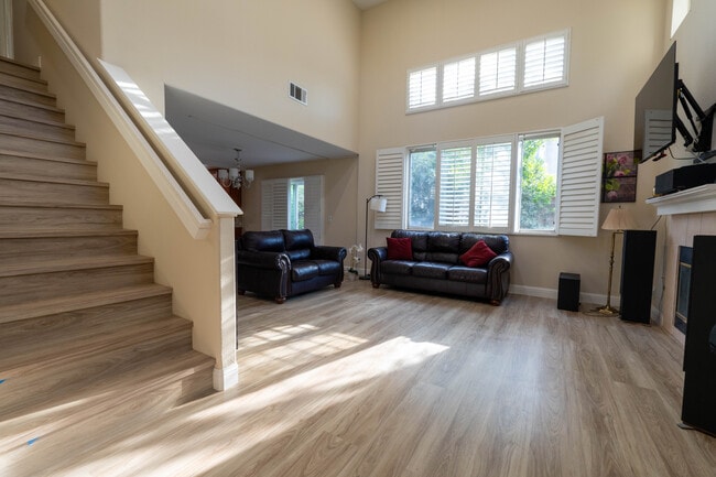 Living room featuring vaulted ceilings, gas fireplace, and smart dimmable recessed LED fixtures. - 8781 Arbor St