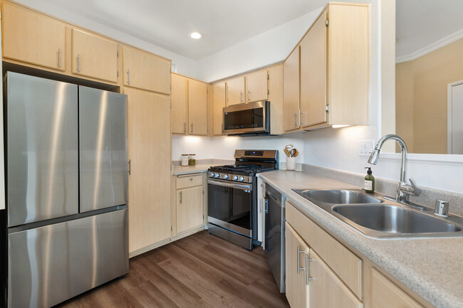 Updated Finishes kitchen with upgraded stainless steel appliances, laminate countertops, oak cabinetry, and upgraded hard surface flooring - Avalon Mission Oaks Apartments