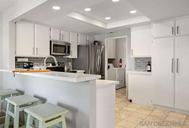Kitchen with island and barstool seating, washer/dryer, leads to attached garage - 3086 Corte Trabuco