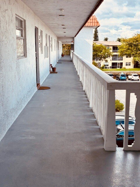 Vista del pasillo cubierto y la puerta principal. - 1400 NE 57th St Unidad Casa Del Sol