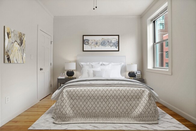 Elegant bedroom with modern decor, featuring a plush bed and stylish artwork, filled with natural light from a large window.