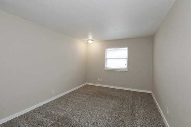Bedroom with carpet flooring, neutral walls, window with blinds, and simple flush mount ceiling light fixture