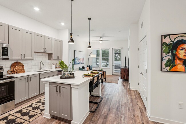 Welcome to your new home. Enjoy you new modern kitchen with a white island and wooden floorsw - Tapestry University Park Apartments