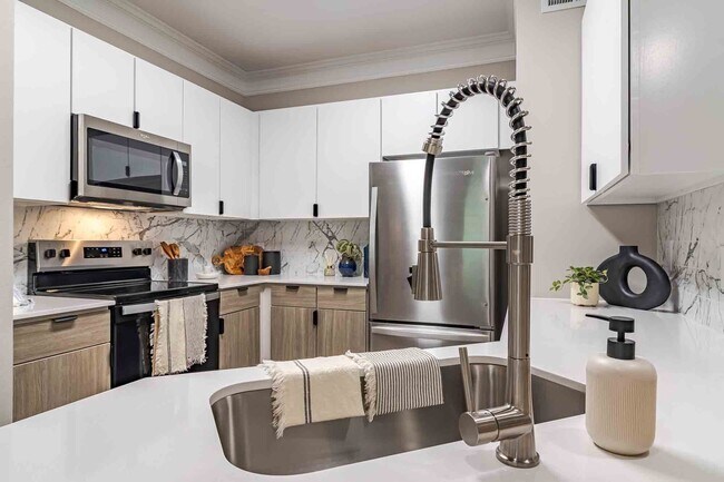 Cocina recién reformada con encimeras de cuarzo, electrodomésticos de acero inoxidable y armarios de dos tonos. - Waterstone at Big Creek Apartments