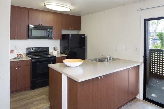 Kitchen with black appliances and hard surface vinyl plank flooring - eaves South Coast Apartments