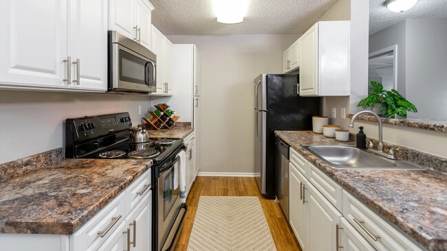 Enjoy cooking in a fully equipped kitchen with sleek stainless appliances, granite-inspired counters, and bright white cabinetry for a clean, modern look. - Grand Oaks At The Lake