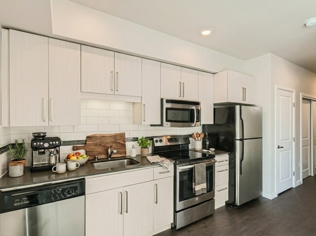 Kitchen at 306 Queen Anne featuring stainless steel appliances, dark countertops, subway tile, and flat-panel cabinets.