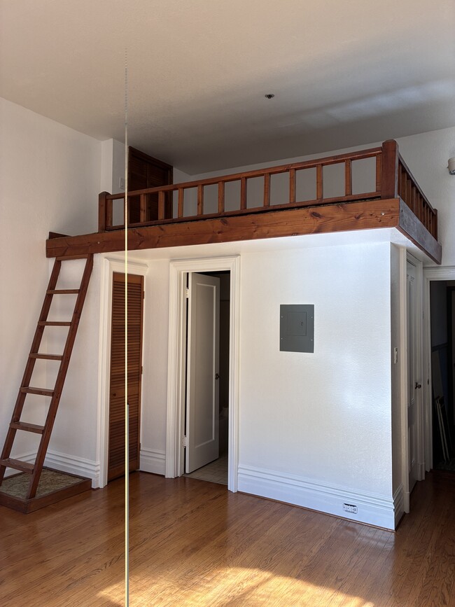 Escalera al altillo, armario de almacenamiento y puerta al baño.