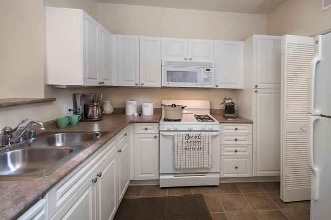 Classic Package I kitchen with white cabinetry, white appliances, laminate countertops, and tile flooring