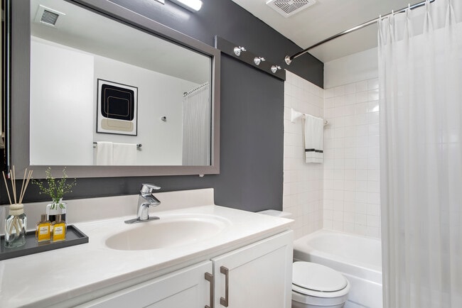 Renovated Package II bath with white countertops and cabinetry, accent wall, and hard surface flooring
