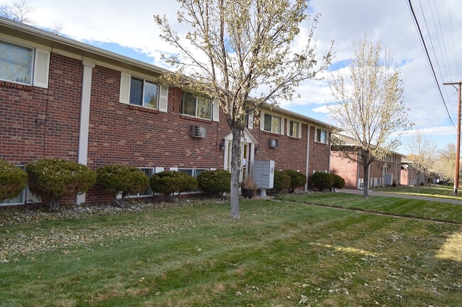 Acogedor complejo de apartamentos de ladrillo con exuberantes jardines verdes, árboles maduros y un entorno de vecindario sereno.