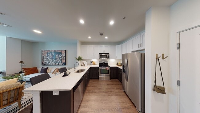 Open kitchen meticulously reimagined with two-tone cabinets, quartz counters, and stainless steel appliances