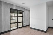 Apartamento moderno de estilo industrial con paredes de hormigón, un gran ventanal y elegantes suelos de madera.