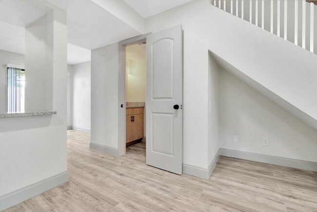 Bright and airy hallway with modern wood flooring, leading to a cozy room under the stairs.