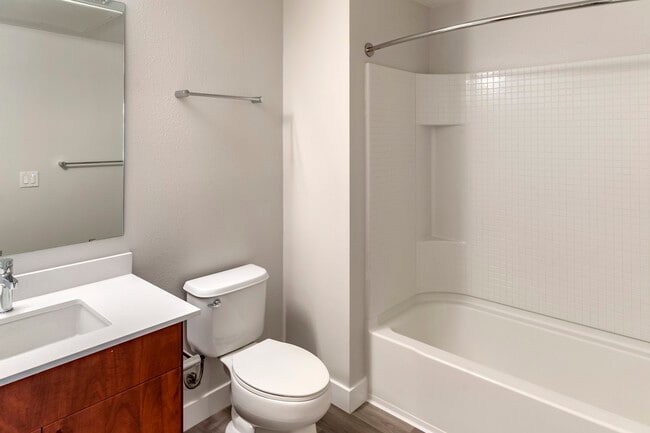 Renovated Package I bath with white quartz countertop, cherry cabinetry, and hard surface flooring