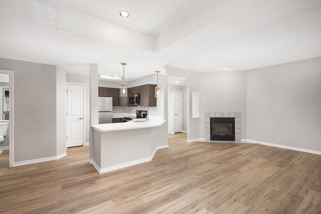 Modern apartment kitchen with elegant white countertops, stainless steel appliances, and warm wood flooring.