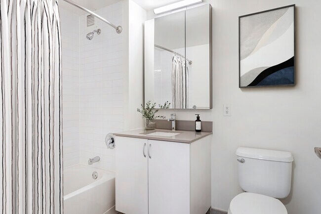 Renovated Package I bath with white cabinetry, grey quartz countertops, and hard surface flooring