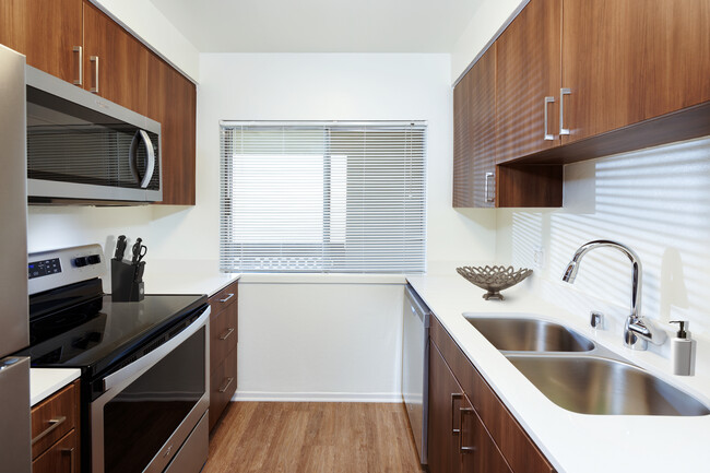 Renovated I kitchen with new cabinetry, quartz countertops, stainless steel appliances, and hard surface flooring - eaves Huntington Beach Apartments