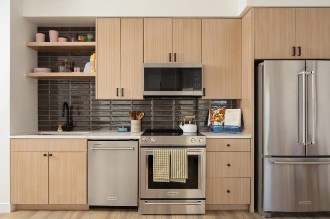 Light wood cabinetry, sleek stainless appliances, and a glossy tile backsplash create a clean, contemporary kitchen with character. - Modera Rio Salado