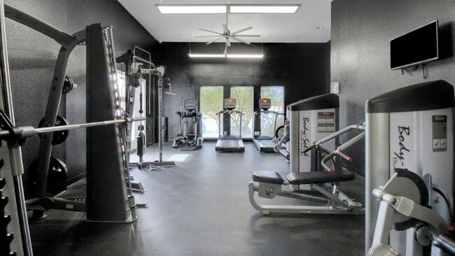 Modern fitness center with state-of-the-art exercise equipment, including treadmills and weight machines in a sleek, well-lit gym space. - Advenir at The Meadows