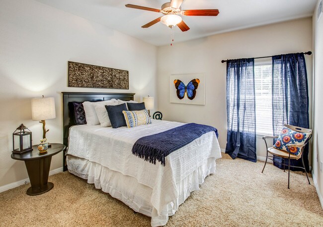 Bedroom with plush carpet, ceiling fan, and large window