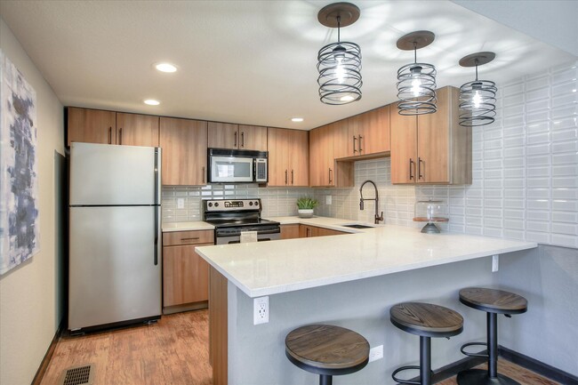 Image of the resident club house kitchen with stainless steel appliances quartz counters and stools. - Chestnut Ridge Apartment Homes