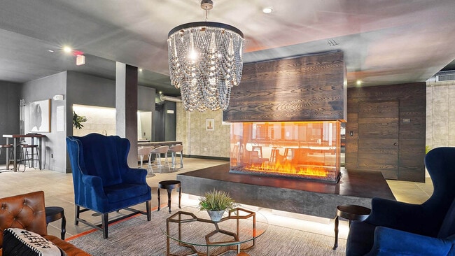 Entertainment lounge with fireplace, plush seating, and elegant chandelier.