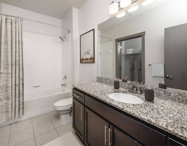 Classic Package II Bath with speckled granite countertop, dark wood cabinetry, and tile flooring