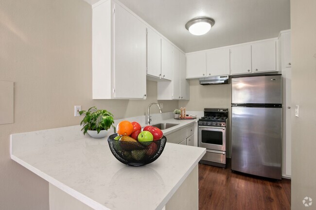 Kitchen with stainless steel two-door refrigerator, gas stove over range hood, white cabinets - Seville Townhouse