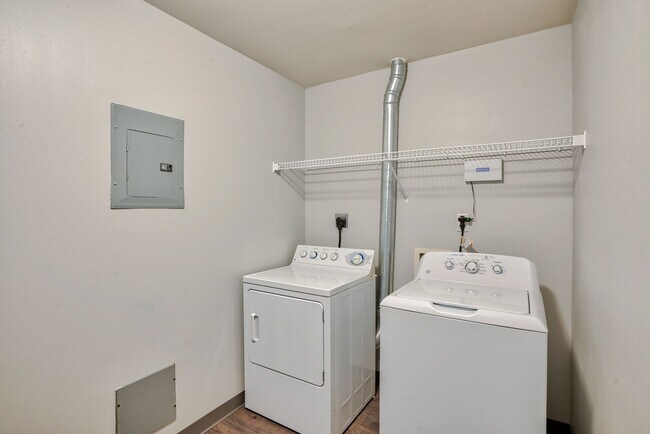 Una lavadora y secadora en una habitación con un estante y piso estilo madera. - Wireworks Lofts