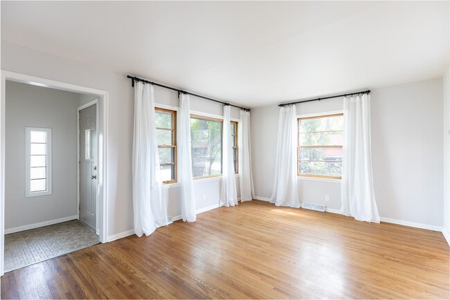 Sala de estar recién pintada con pisos de madera originales y toneladas de luz natural. - 3118 28th Ave S Casa Adosada