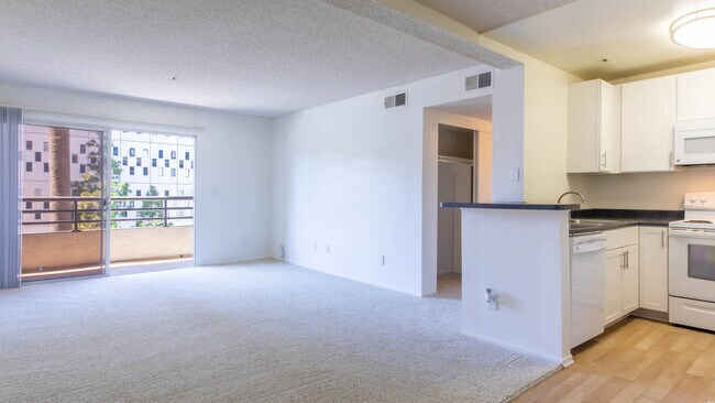 Kitchen and Carpeted Living Room with Balcony