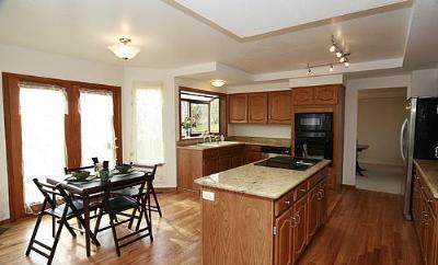 Kitchen island with cooktop, wall oven, microwave, window well, eating space, pantry, lots of cabinet space, hardwood floors. - 6782 Swadley Court