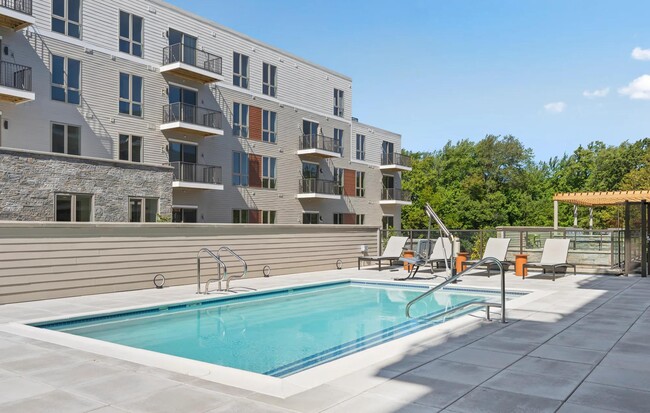 Resort-style pool with sundeck and chaise lounges. - Modera Newton Apartments